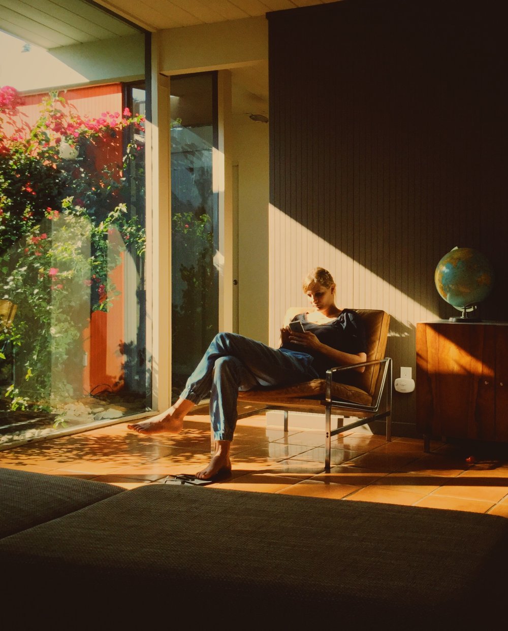 A woman using a phone while sitting on a chiar